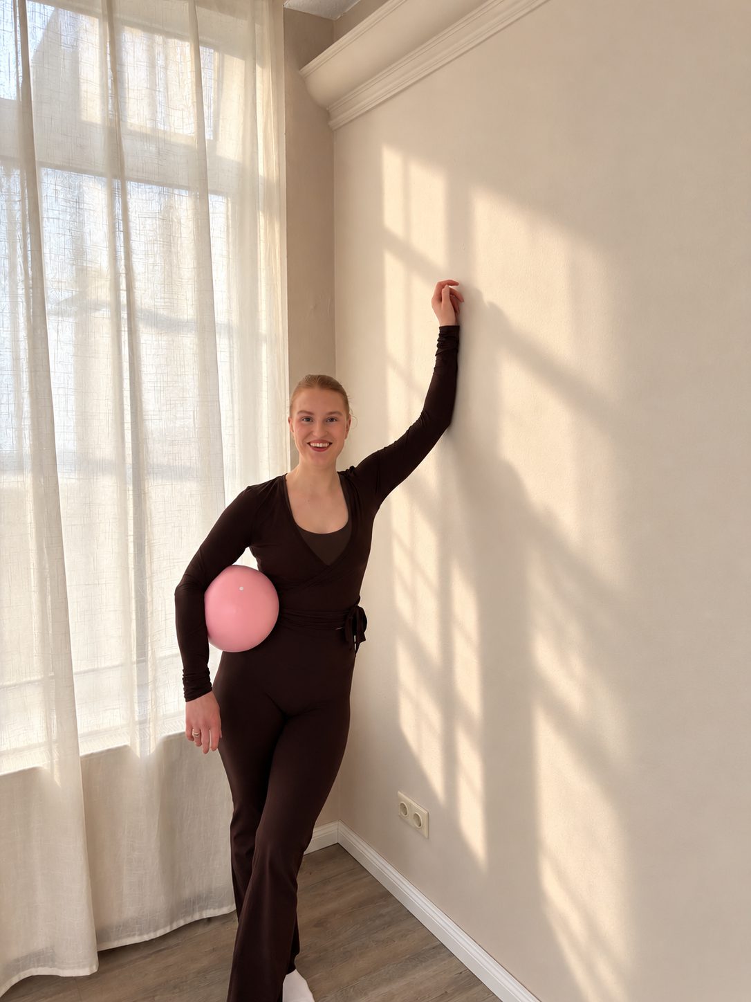 Stehend im Sonnenlicht mit Pilates-Ball