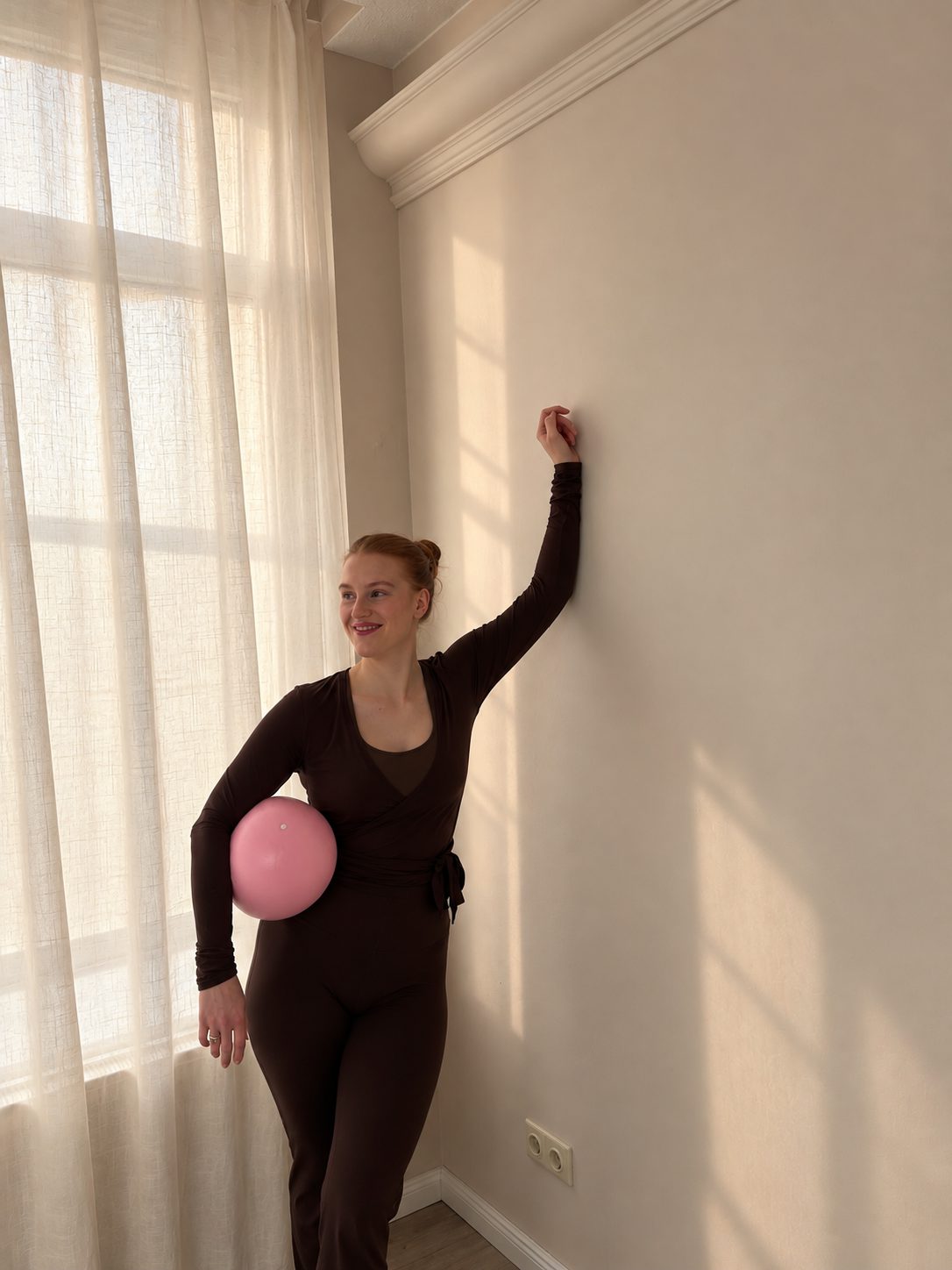 Selina sitzt lächelnd und umarmt den Pilates-Ball