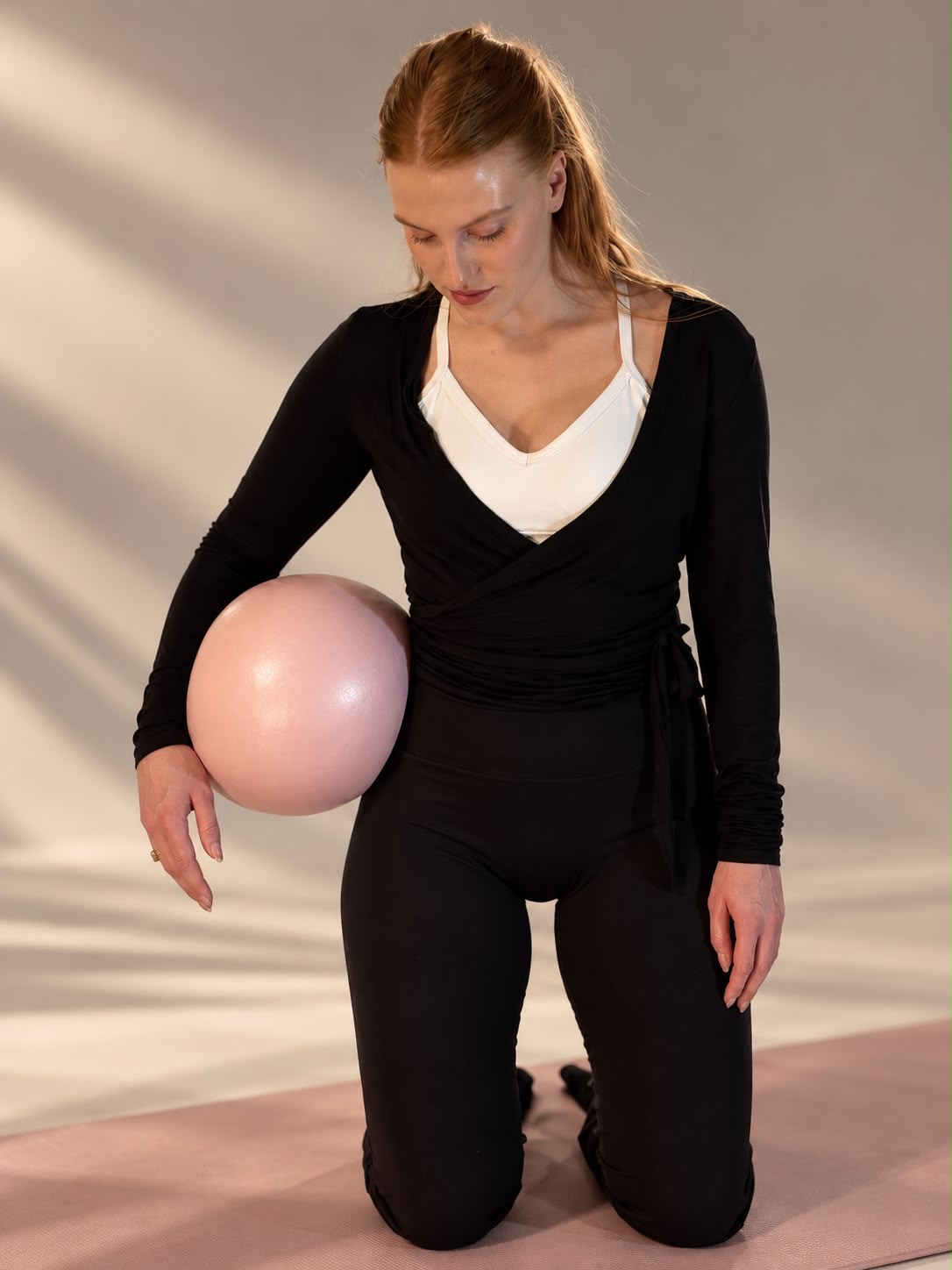 Kniend mit Ball an der Hüfte